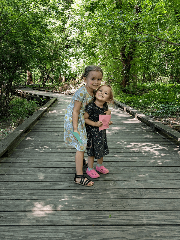 Two young girls hugging on a wooden boardwalk